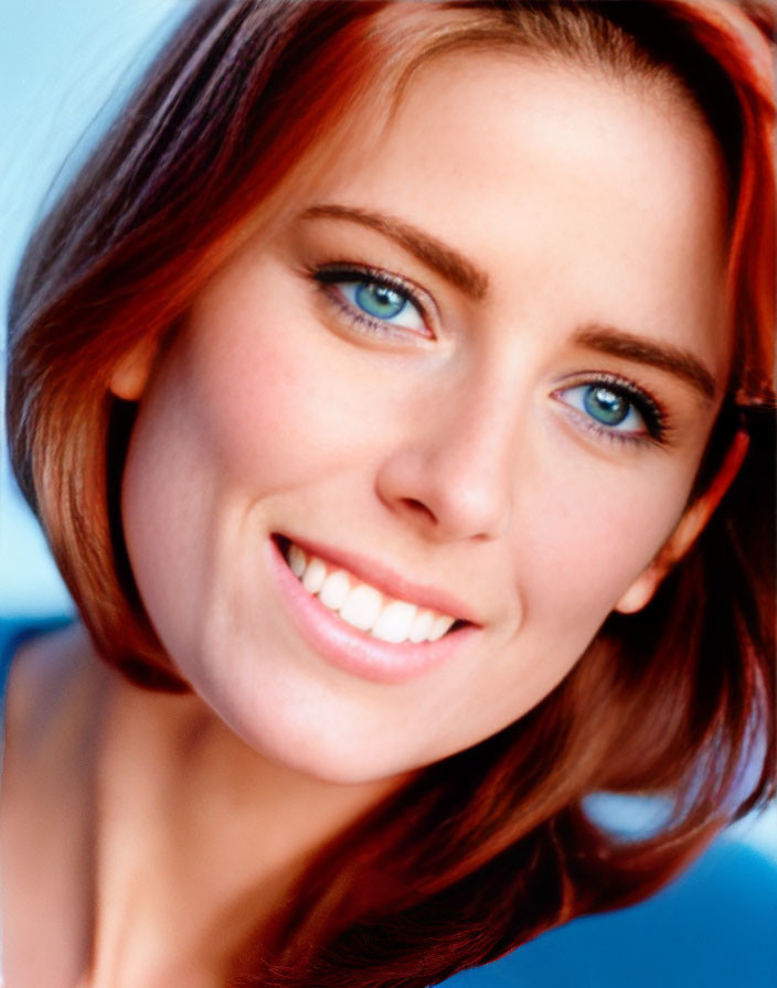 Smiling woman with red hair, blue eyes on blue background