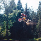 Motorcyclist mid-air jump with motion blur background of trees
