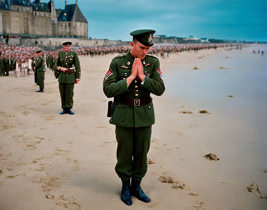Soldier in uniform praying on beach with formation of soldiers in background