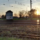 Solitary figure in coat and hat by railway watching old-fashioned railcar at sunrise or sunset
