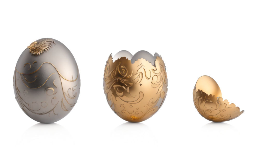 Three ornate spherical objects with intricate designs and cracked eggshell-like portions on white background.