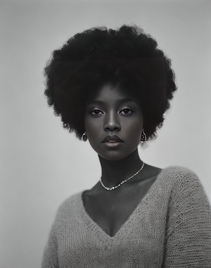 Contemplative woman with afro hairstyle in grayscale portrait
