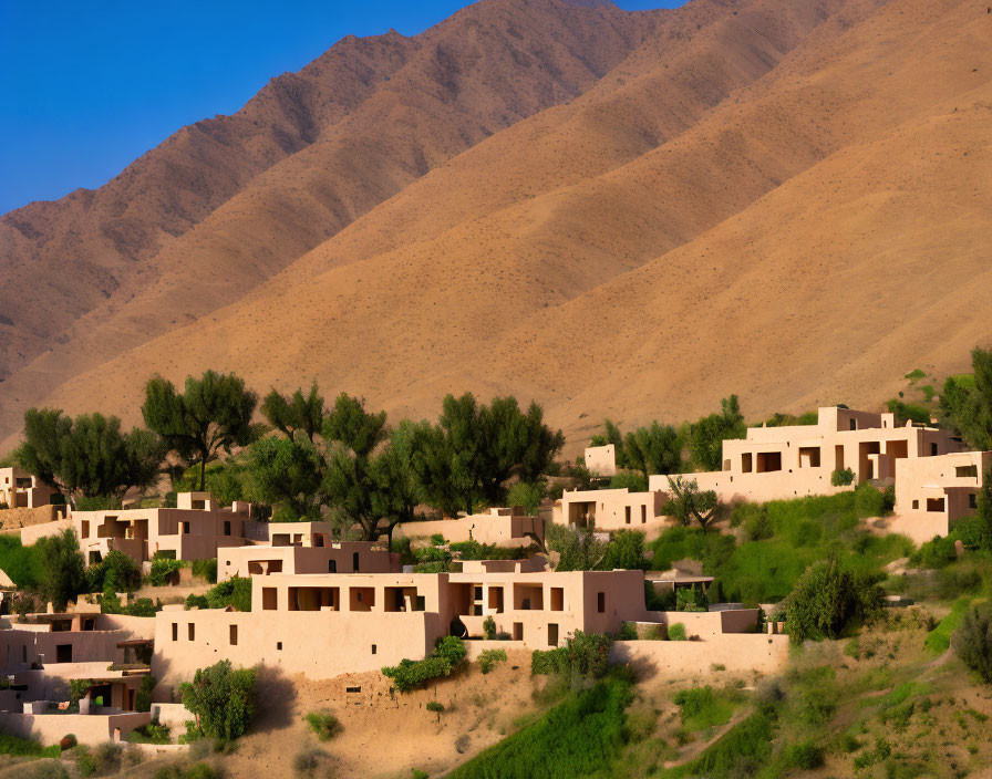 Traditional village with earthen buildings in barren mountain range landscape