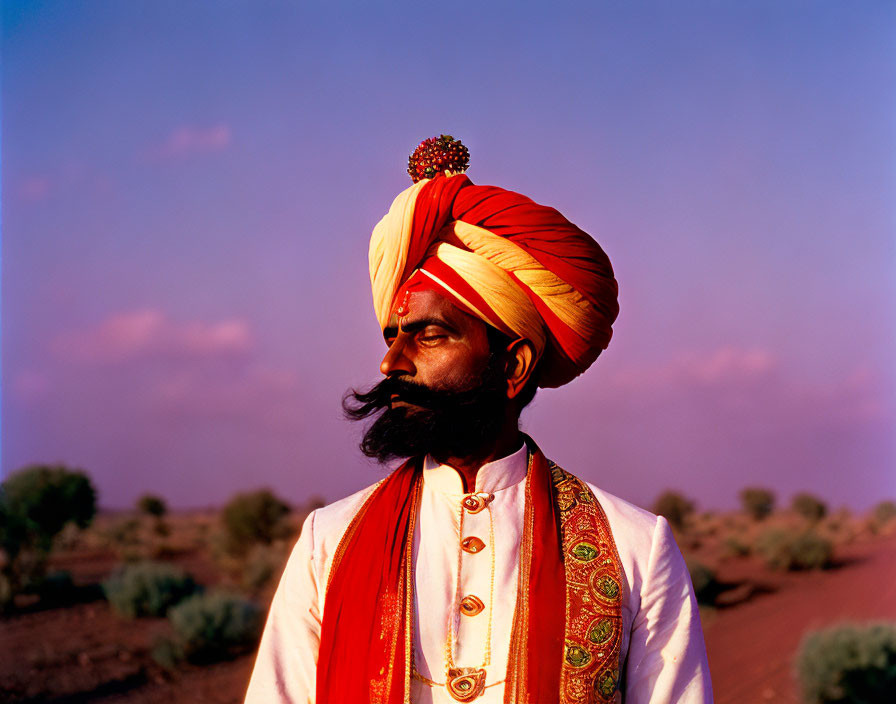 Man in Colorful Turban and Traditional Attire in Desert Landscape