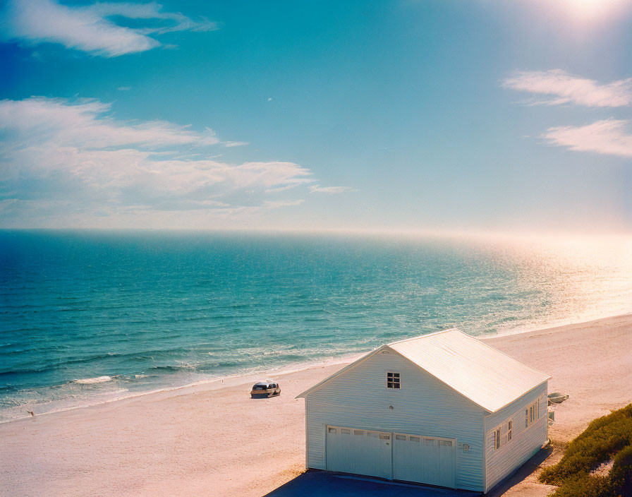 White Garage by Sandy Beach with Car Under Blue Sky and Sunlit Clouds
