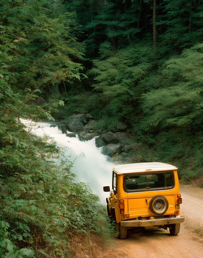 Yellow Off-Road Vehicle Parked Near Rushing Waterfall in Forest
