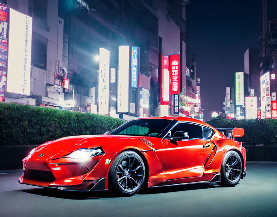 Vibrant red sports car parked on city street at night surrounded by illuminated billboards.