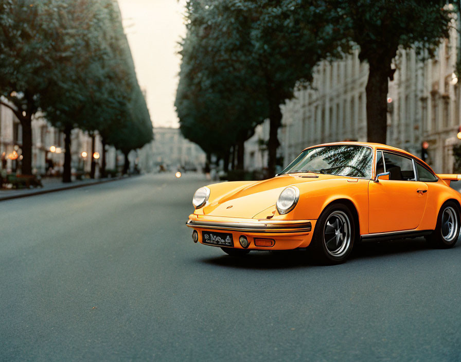 Vintage Orange Porsche 911 on Tree-Lined Street at Dusk