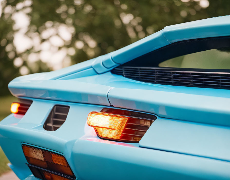 Vintage light blue sports car rear end with unique taillights and spoiler in close-up view.