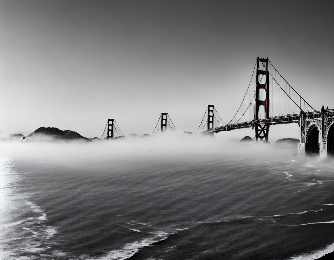 Iconic Golden Gate Bridge shrouded in fog with hill silhouettes and boat in view