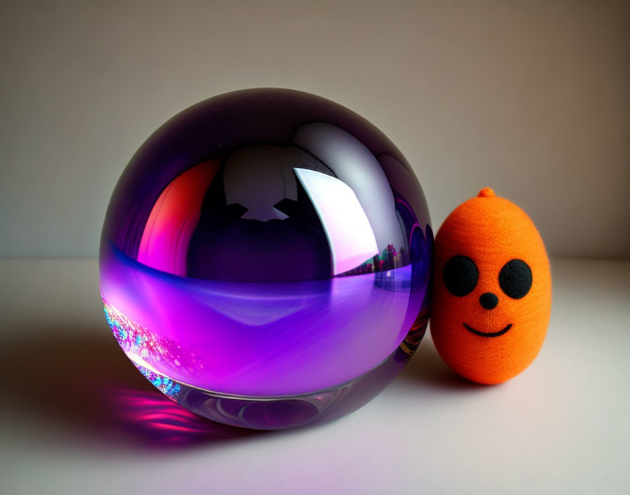 Purple Glass Orb and Smiling Orange Plush Toy with Black Features