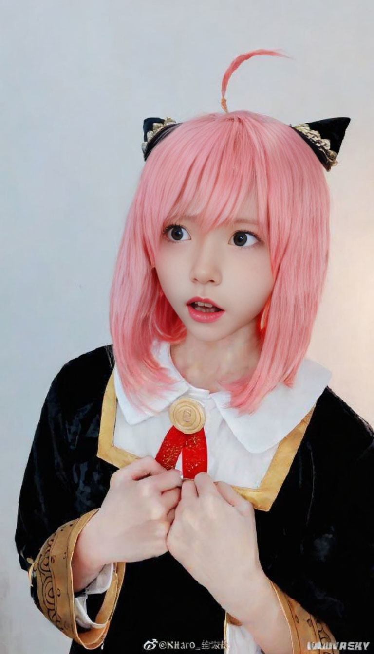 Anime character cosplay with pink hair, cat ears, black and gold outfit, and red amulet.