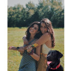 Two girls, two black dogs in field at golden hour