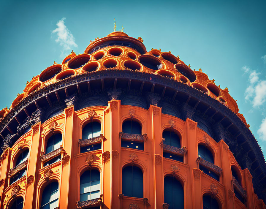 Orange multi-tiered building with intricate balconies against clear blue sky