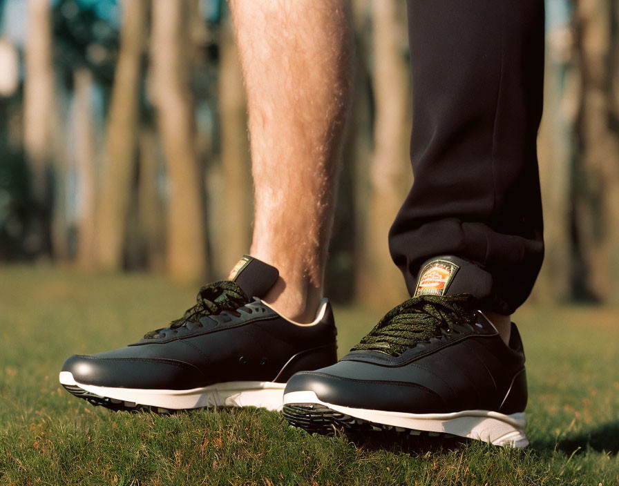Person's Lower Legs in Black Sneakers on Grass