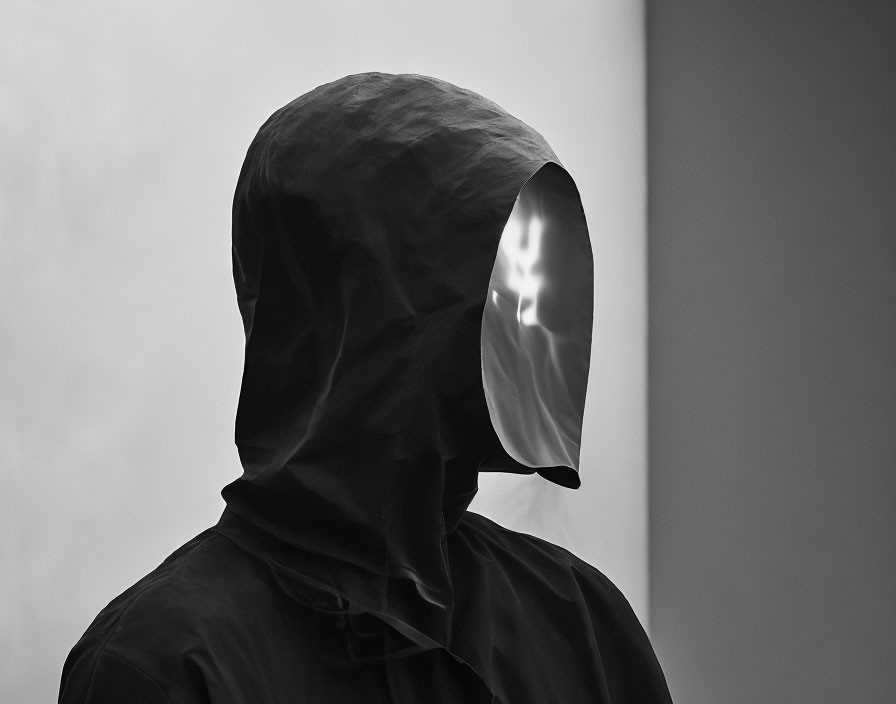 Person in Black Hood with Reflective Face Visor on Neutral Background