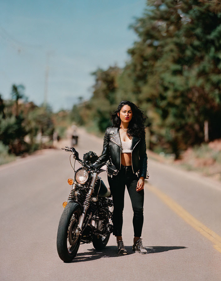 Woman in Black Leather Jacket and Jeans with Motorcycle on Open Road