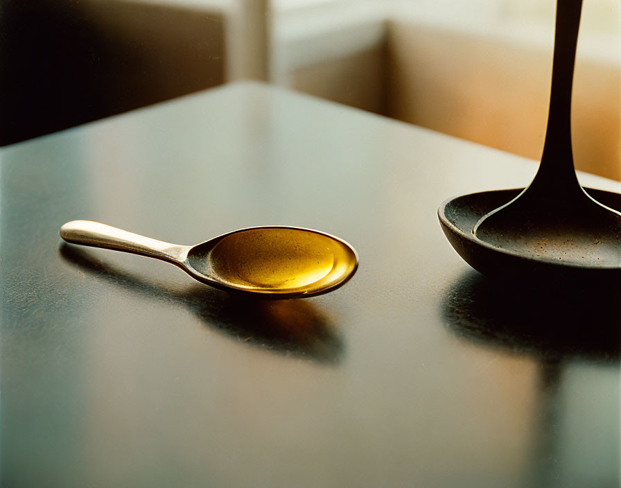 Close-up Photo: Spoon on Reflective Surface with Golden Liquid