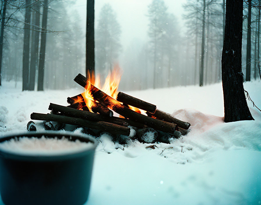 Wintry forest scene with burning campfire and steaming cup