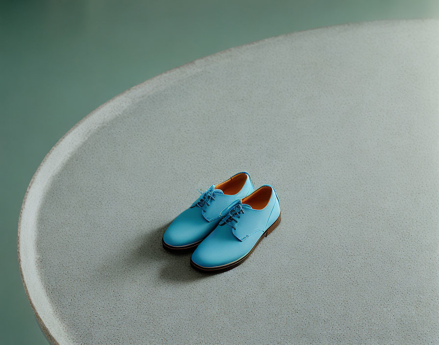 Blue Dress Shoes with Orange Soles on Grey Surface and Green Background