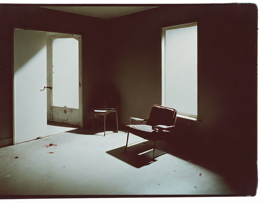 Empty dimly lit room with chair, stool, open door, two windows, and scattered debris.