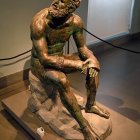 Bronze sculpture of seated contemplative man with golden patina