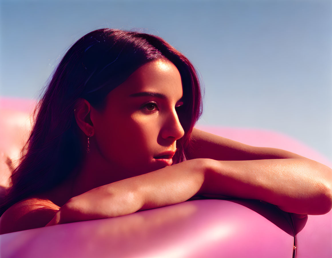Woman relaxing on inflatable under pink and blue sky
