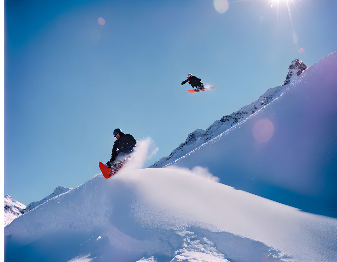 Snowboarders catching air on sunny snow-covered mountain slope.