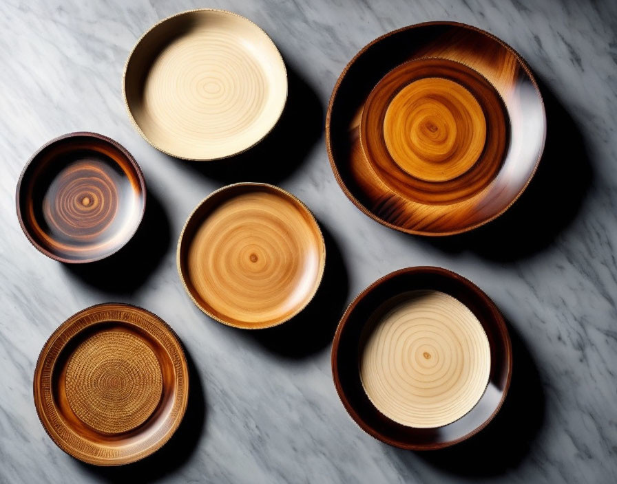 Assorted wooden bowls with circular patterns on marble surface