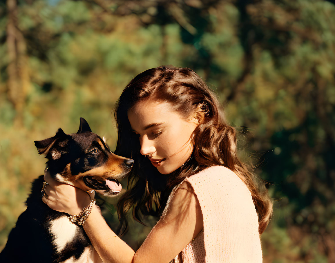 Young woman in knit top with black and tan dog in sunlit natural setting