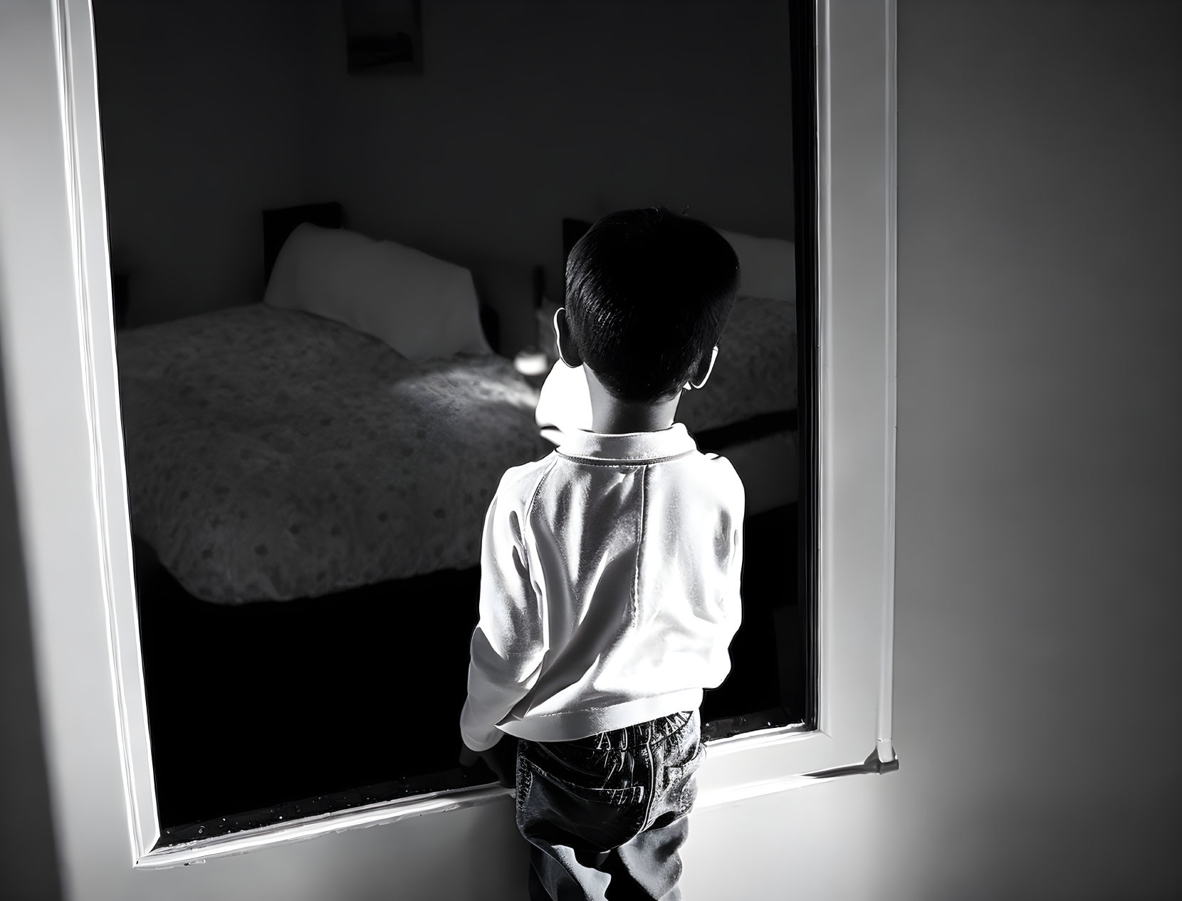 Child looking out of window into dark room with sunlight silhouette