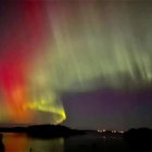 Vibrant aurora borealis over coastal landscape at night