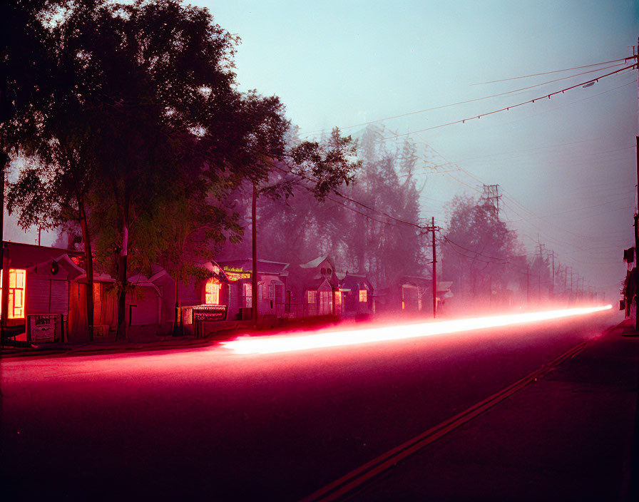 Long-exposure photo of ghostly car lights on suburban street at dusk