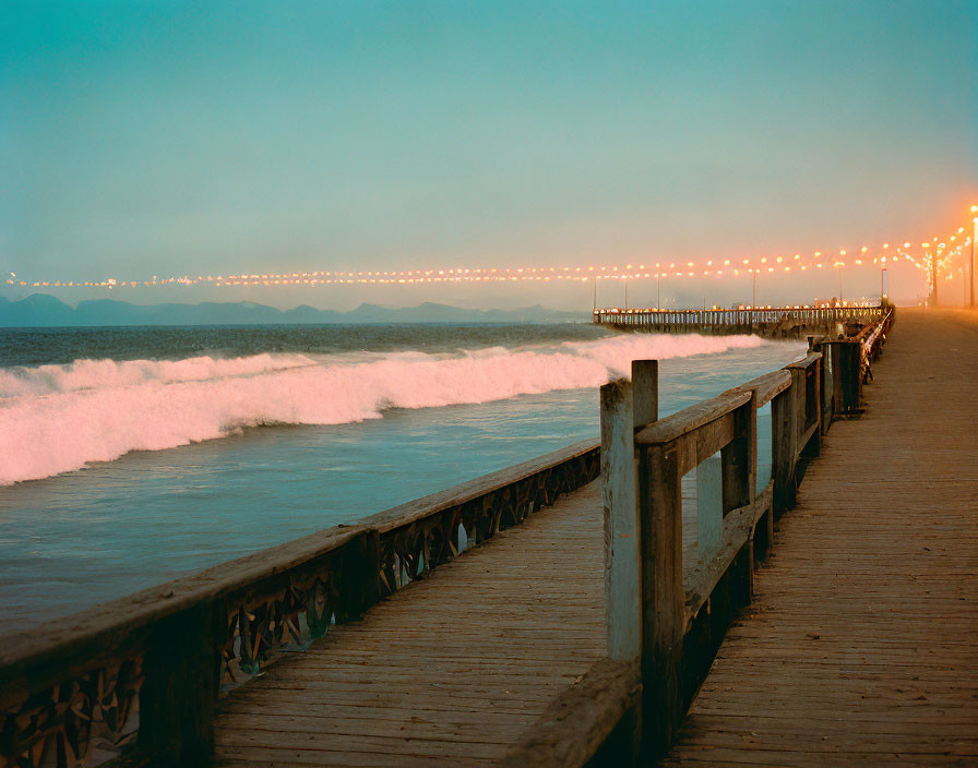 Ocean pier at twilight with waves and street lamps