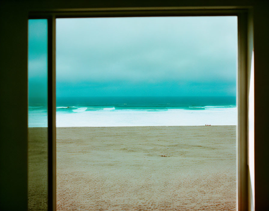 Tranquil beach scene through a window: sandy shore, calm blue waters, hazy sky