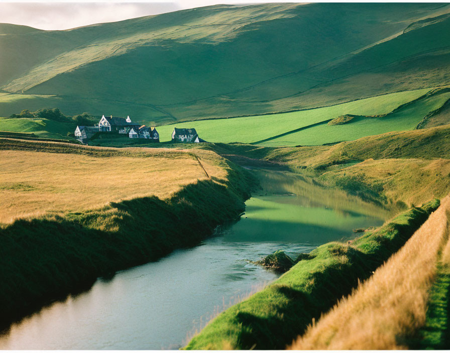 Tranquil landscape with houses, green hills, and river.