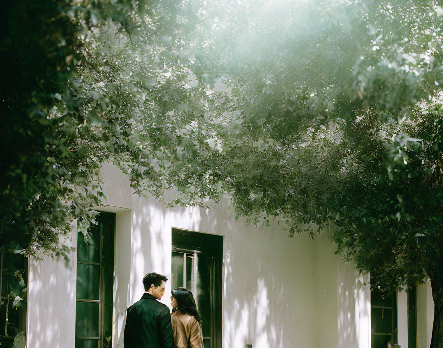 Intimate moment of a couple under dappled light by building