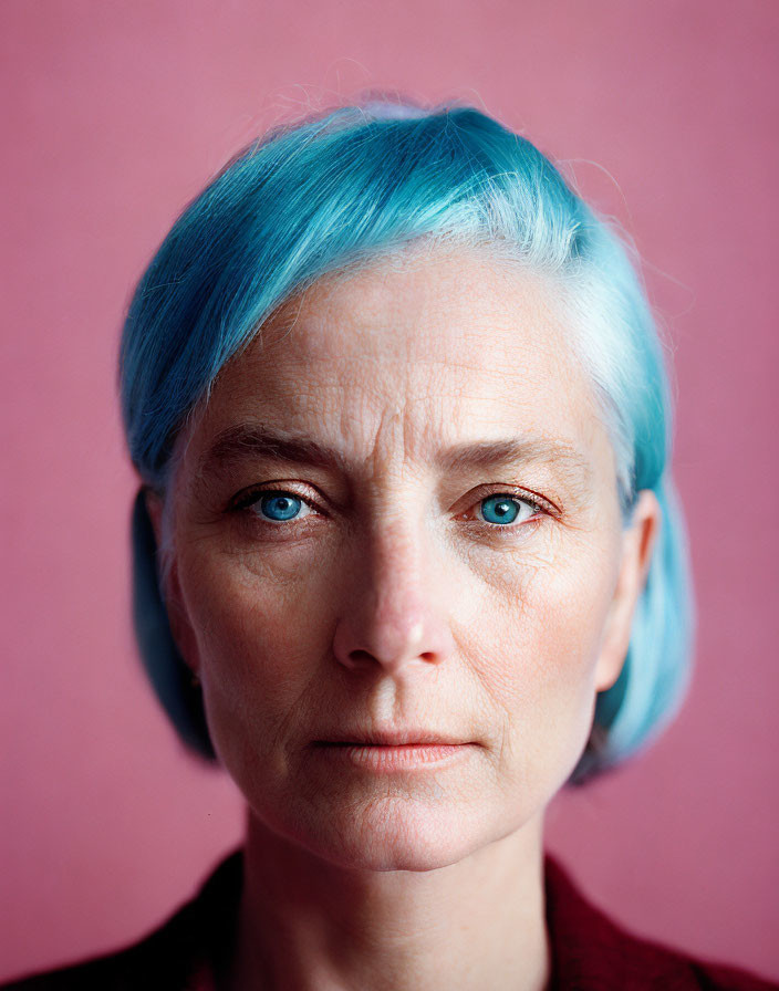 Woman with Blue Hair and Striking Blue Eyes on Pink Background