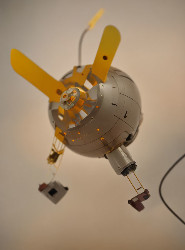 Model spacecraft with gold solar panels, antennae, and instruments on beige background