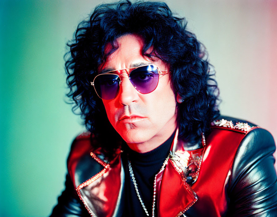 Curly-Haired Man in Sunglasses with Red Leather Jacket on Colorful Background