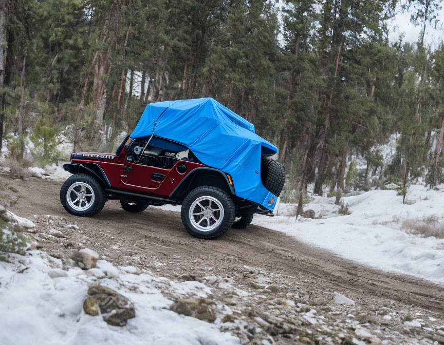 Red Jeep with Blue Tarp Cover Parked on Snowy Forest Road