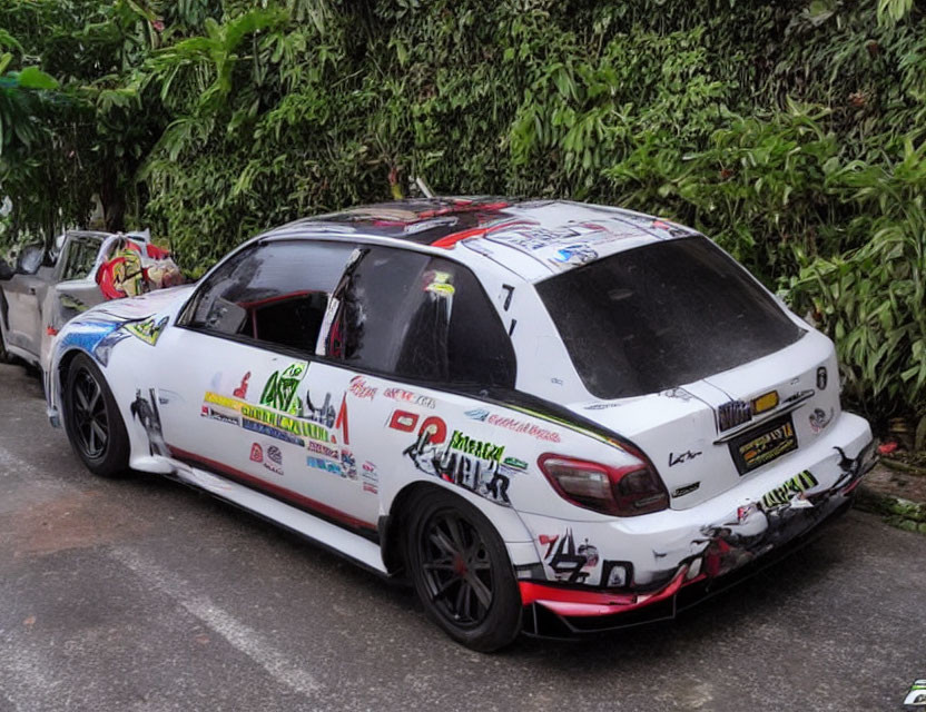 White Racing Car with Red and Blue Graphics and Sponsor Decals Parked by Roadside