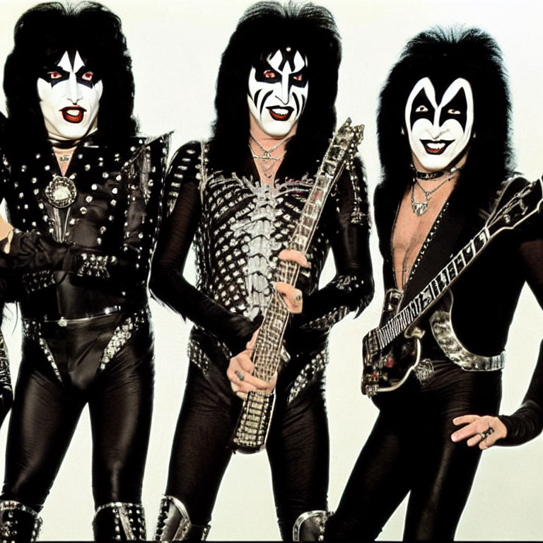 Three individuals in black and silver stage outfits with face paint - promotional photo.