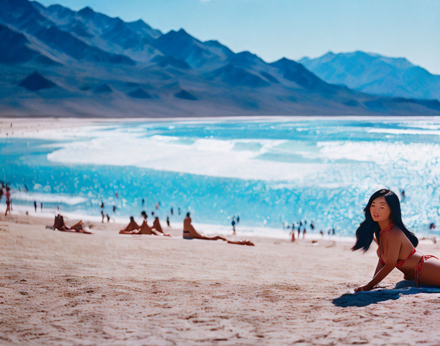 Person in Red Swimsuit on Sandy Beach with Blue Waters and Mountains