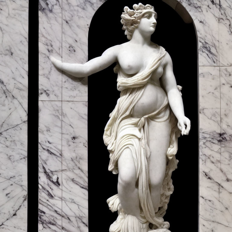 Classical marble statue of female figure with drapery against arch background