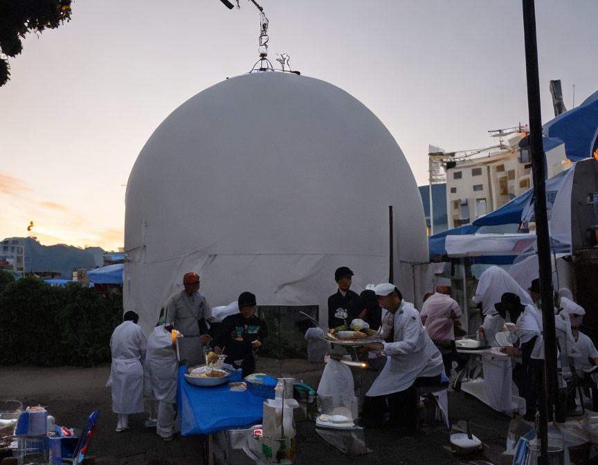 Chefs in white uniforms cooking under large canopy at outdoor event