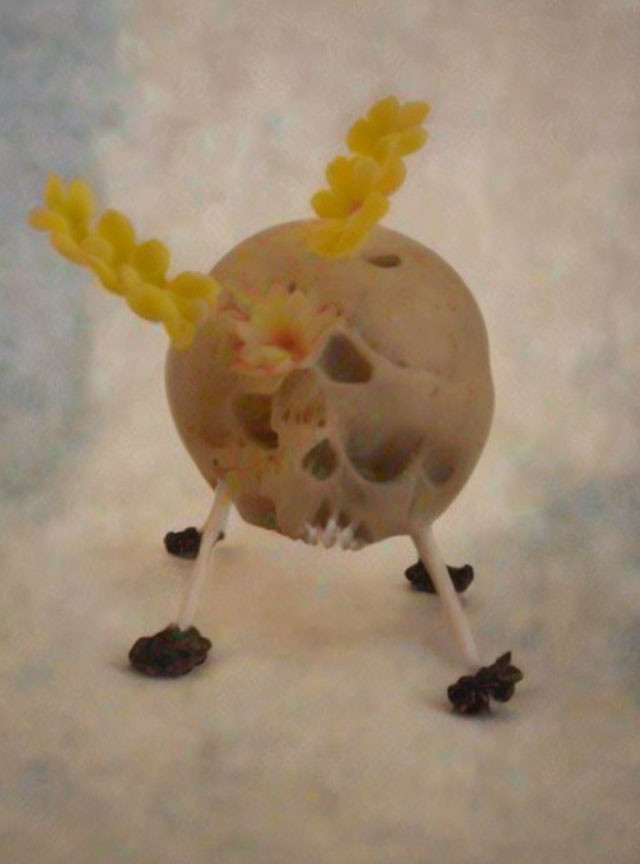 Skull sculpture with yellow flower horns and bird-like legs walking