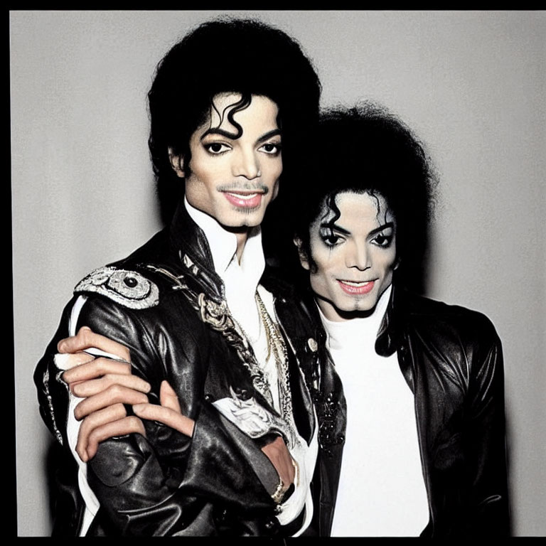 Two Michael Jackson look-alikes in matching black outfits and makeup against grey backdrop