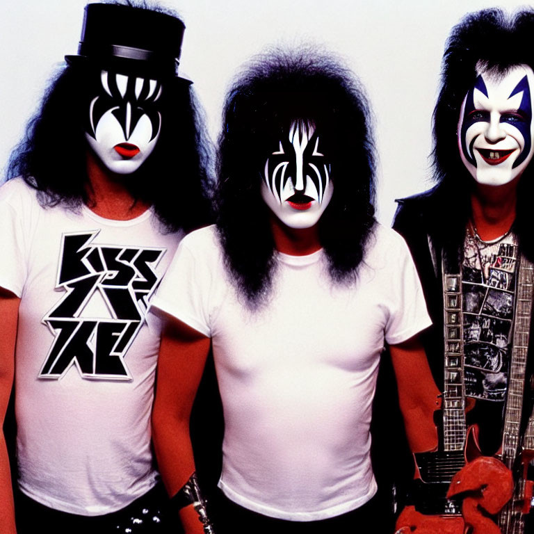 Three individuals in KISS-inspired makeup, black and white attire, two with guitars
