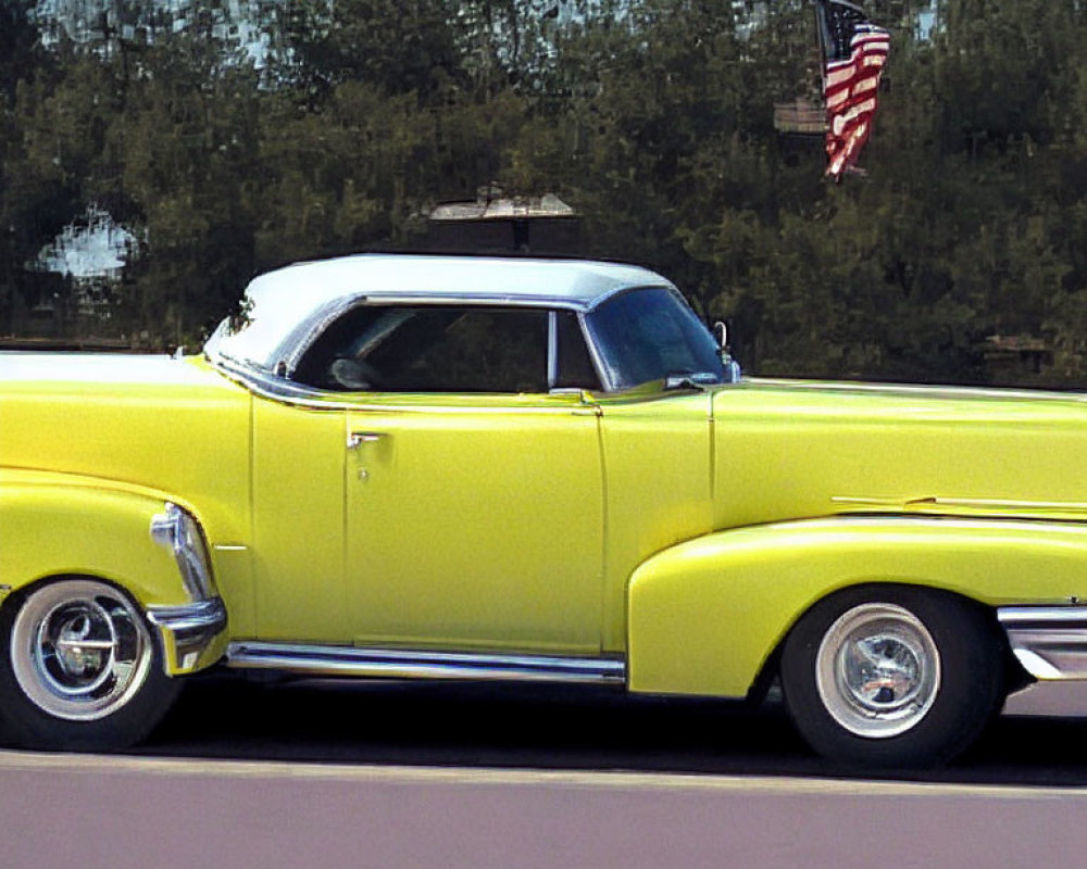 Vintage yellow car with white roof and American flag on the road